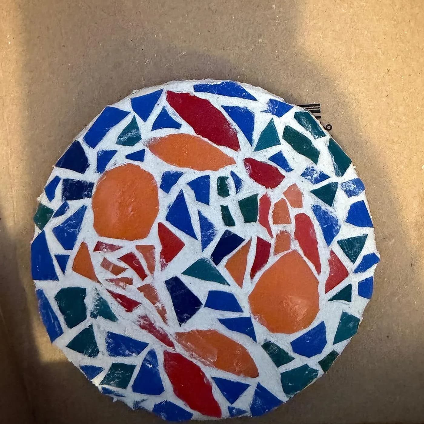 Dessous de plat rond, bleu et orange, mosaïque réalisée chez Artichaut à Montmartre